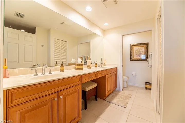 Bathroom featuring light tile patterned floors, double vanity, recessed lighting, and a closet