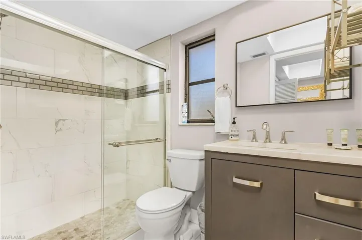 Full bath featuring vanity, a stall shower, toilet, and visible vents