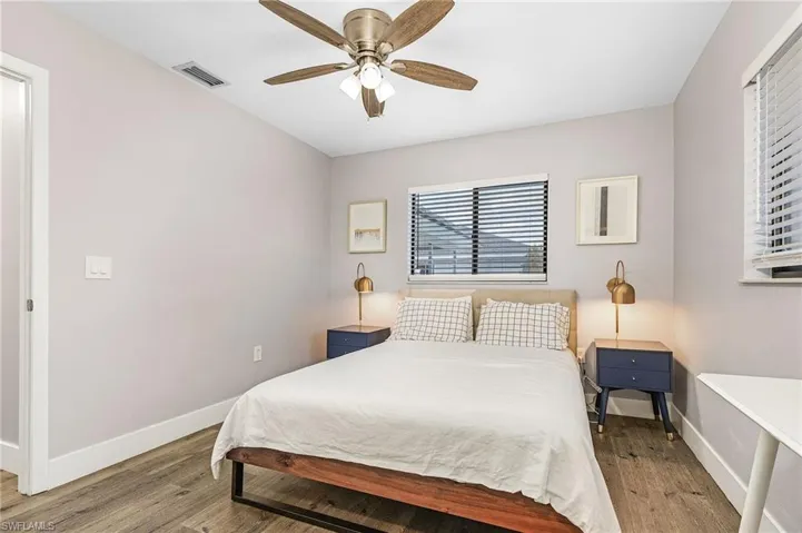 Bedroom featuring ceiling fan, baseboards, visible vents, and wood finished floors