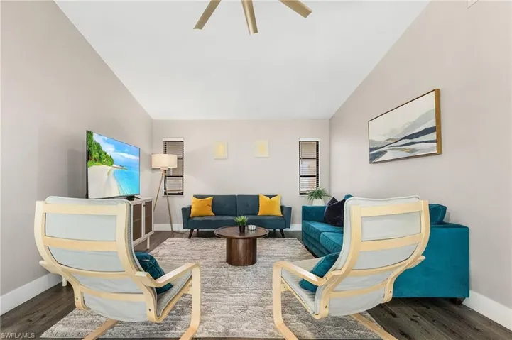 Living area with baseboards, ceiling fan, wood finished floors, and vaulted ceiling