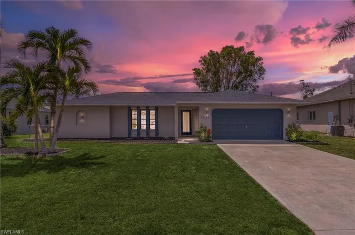 View of front of house featuring a garage, stucco siding, concrete driveway, and a front lawn
