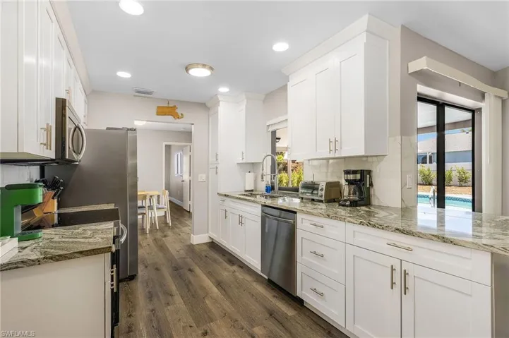 Kitchen with white cabinets, appliances with stainless steel finishes, a sink, baseboards, and visible vents
