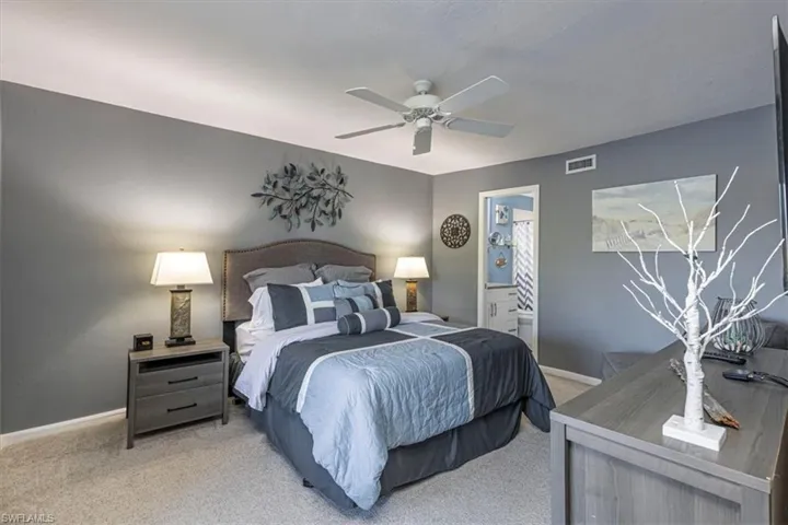 Carpeted bedroom with ceiling fan and ensuite bath