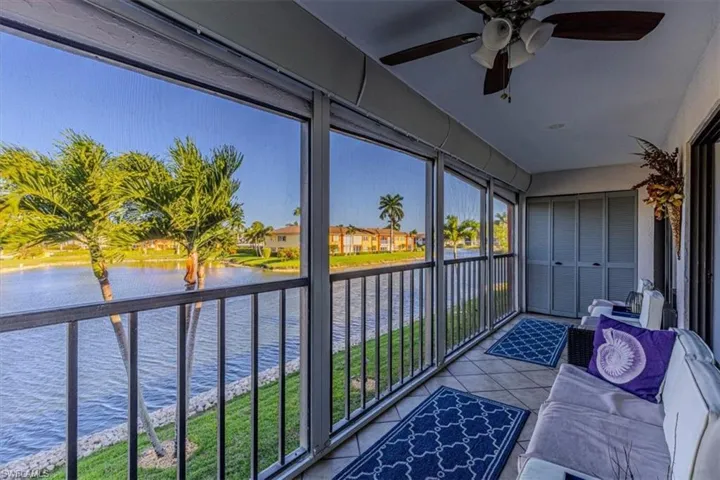 Sunroom with a water view, a ceiling fan, and tile patterned floors