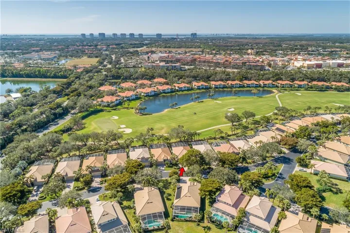 View of property location (red arrow) facing southwest golf fairway and lake beyond. Water on horizon is the Gulf of America. 20 minutes to The Commons Club private beach pavilion, 20 minutes to airport and 5 minutes to Coconut Point open mall shopping, dining and entertainment.