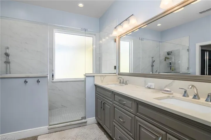 Master bath with marble finish walk-in shower, double vanity, and recessed lighting