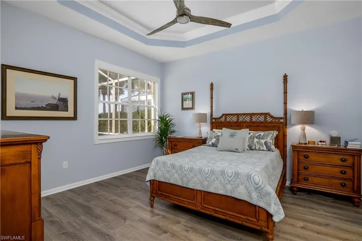 Master bedroom featuring a tray ceiling, luxury vinyl plank flooring (there is no carpet in house), crown molding, and new ceiling fan