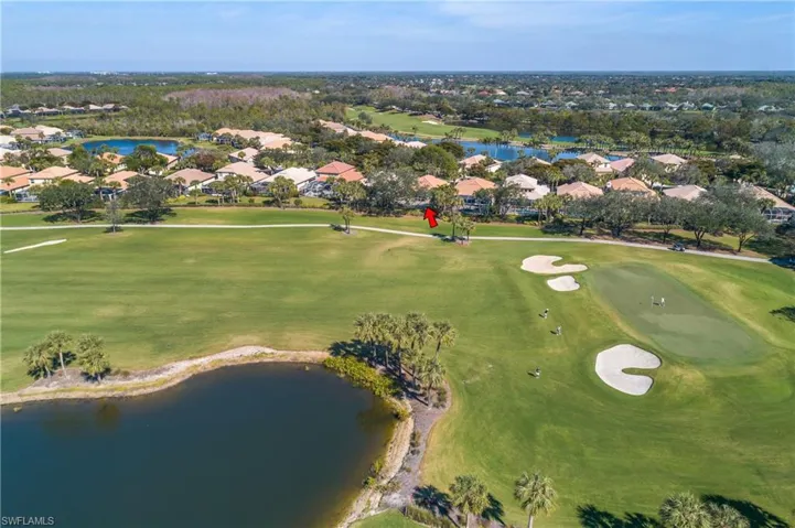 Aerial view of property and surrounding area featuring fairway and lake.