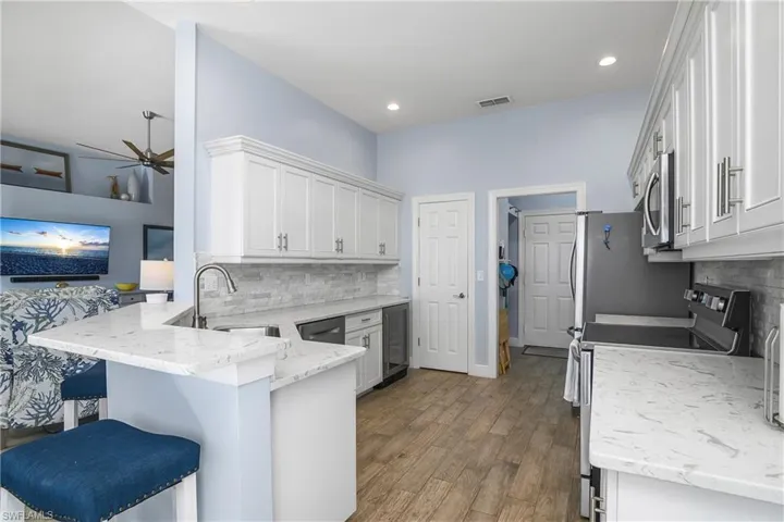View from dining area showing great room, door (closed) to walk-in pantry, utility room and door to garage. Wine cooler appliance near pantry.