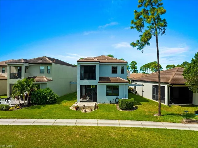 Mediterranean / spanish house with a front lawn, a tiled roof, and stucco siding