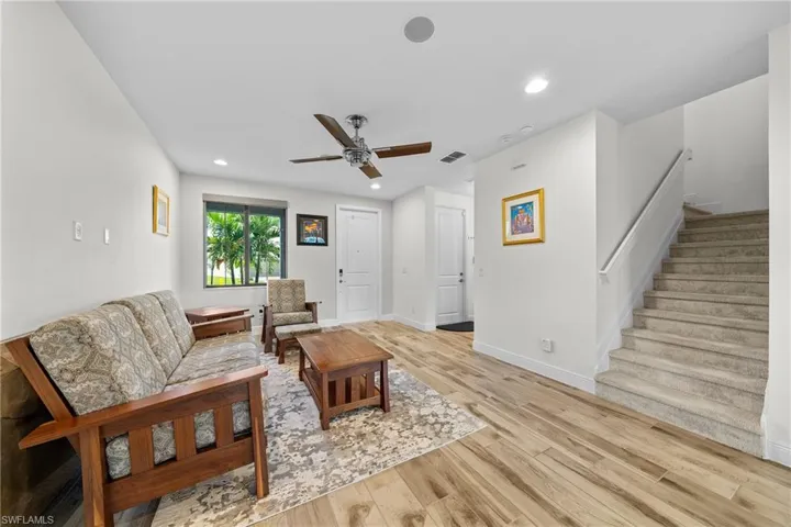 Living area with recessed lighting, light wood finished floors, stairway, and a ceiling fan