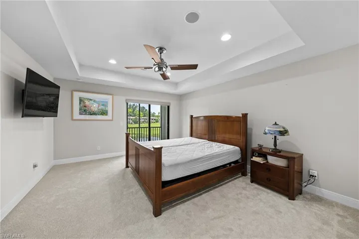 Bedroom featuring a raised ceiling, access to outside, ceiling fan, light colored carpet, and recessed lighting