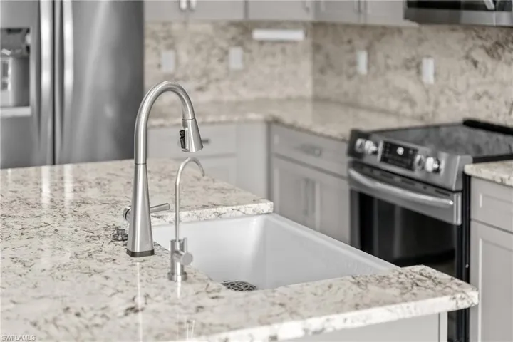 Kitchen with stainless steel appliances, light stone counters, and tasteful backsplash