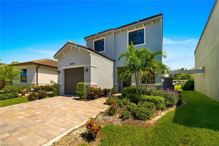 View of front of home with stucco siding, an attached garage, a front lawn, and decorative driveway