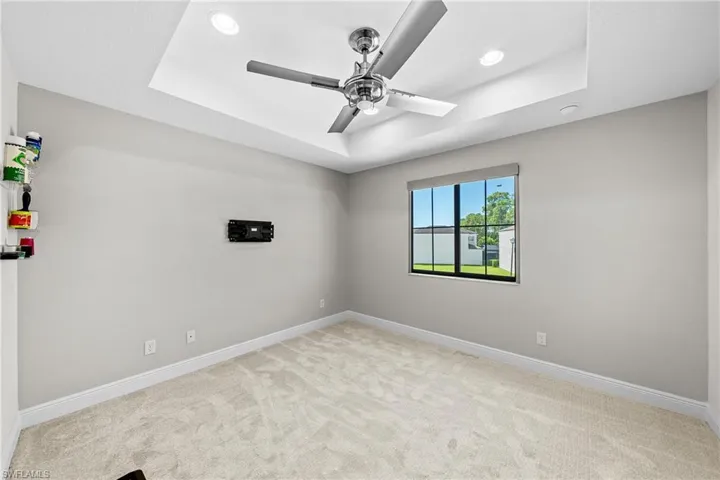 Spare room with a raised ceiling, light colored carpet, a ceiling fan, and recessed lighting