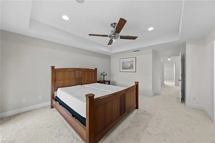 Bedroom featuring a tray ceiling, light colored carpet, ceiling fan, and recessed lighting