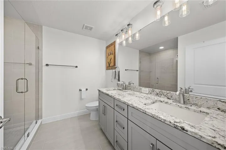 Bathroom with double vanity, a stall shower, and light tile patterned floors