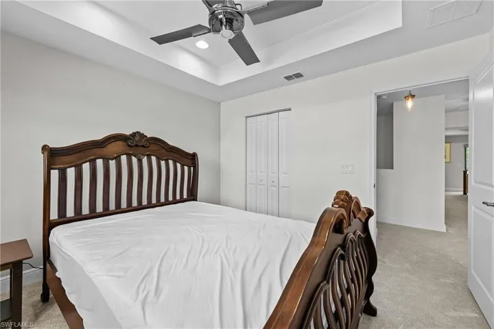Bedroom featuring a tray ceiling, light carpet, ceiling fan, a closet, and recessed lighting