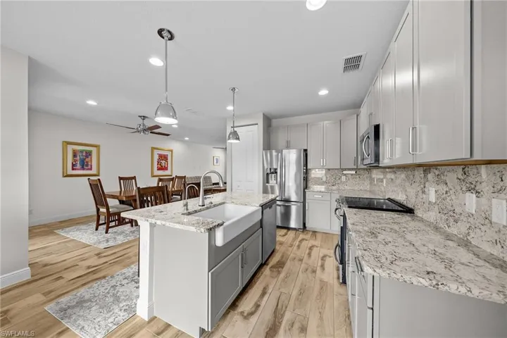 Kitchen with tasteful backsplash, gray cabinets, a ceiling fan, stainless steel appliances, and light stone countertops