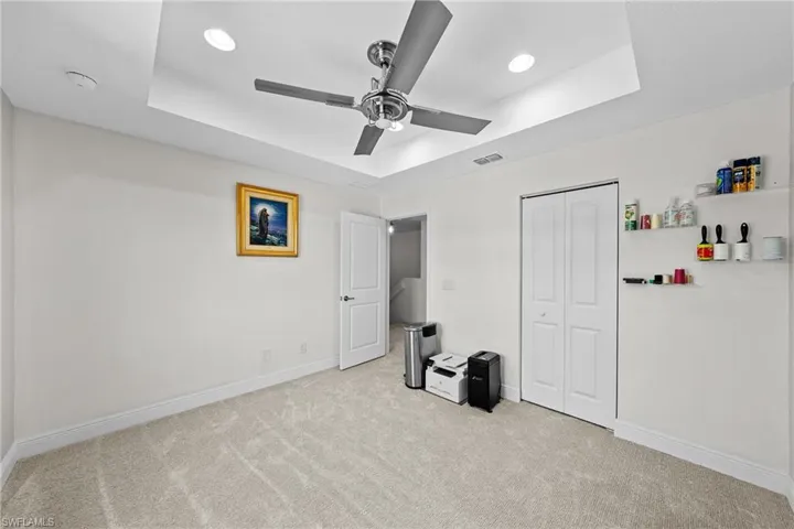 Unfurnished bedroom featuring a tray ceiling, light carpet, ceiling fan, and recessed lighting