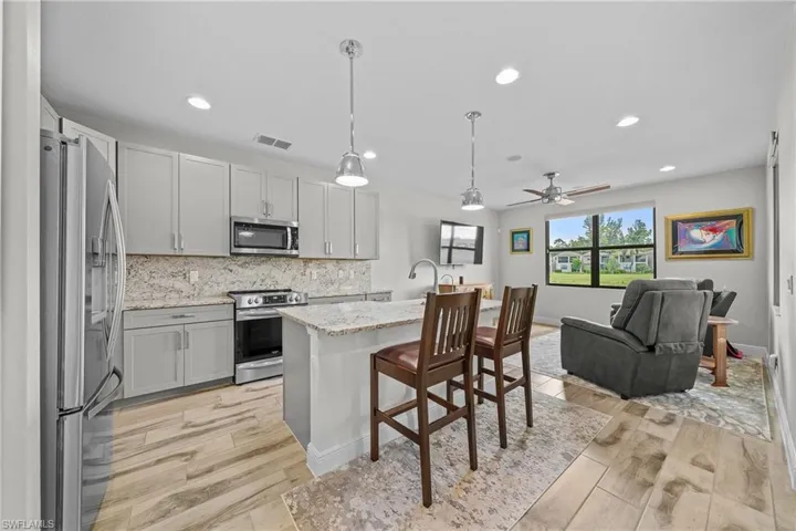 Kitchen featuring ceiling fan, stainless steel appliances, tasteful backsplash, hanging light fixtures, and a kitchen breakfast bar