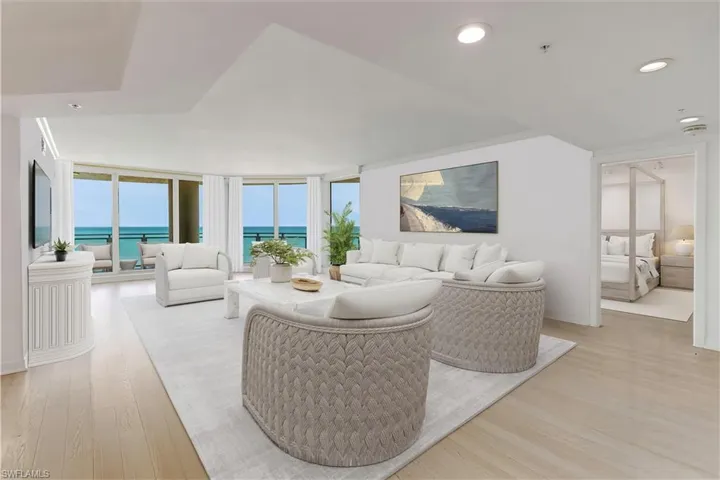 VIRTUAL STAGED Living area featuring light wood finished floors, a water view, expansive windows, and recessed lighting