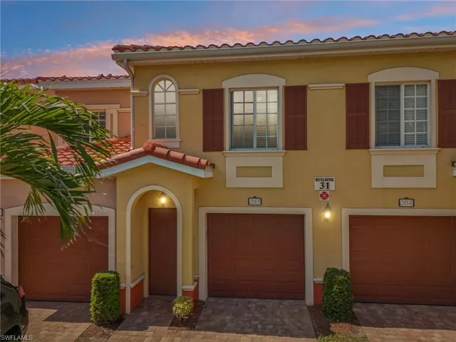View of front of home with decorative driveway, a tile roof, stucco siding, and a garage