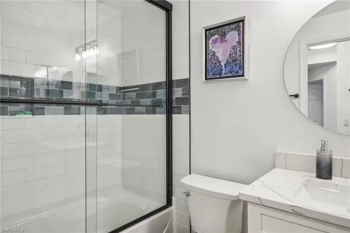 Full bath featuring enclosed tub / shower combo, toilet, and vanity