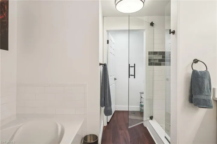 Full bathroom featuring a stall shower, wood finished floors, and a garden tub