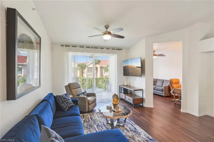 Living room featuring a wealth of natural light, ceiling fan, and dark wood-type flooring