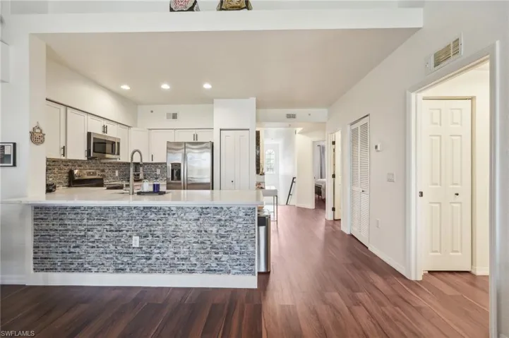 Kitchen with light countertops, stainless steel appliances, a sink, white cabinets, and a peninsula