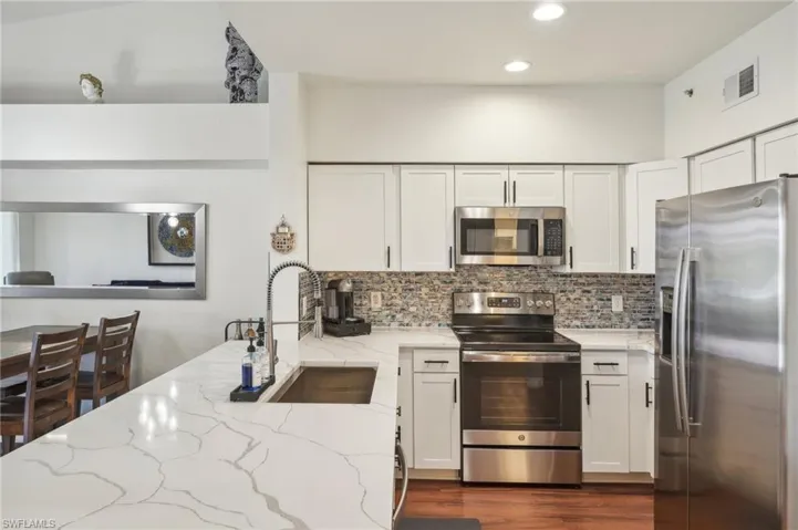 Kitchen with tasteful backsplash, a sink, visible vents, light stone countertops, and appliances with stainless steel finishes