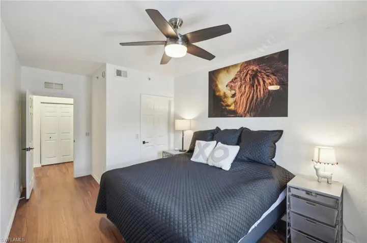 Bedroom with wood finished floors, baseboards, ceiling fan, and visible vents