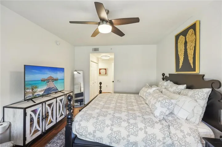 Bedroom featuring dark wood-style floors, ceiling fan, and visible vents