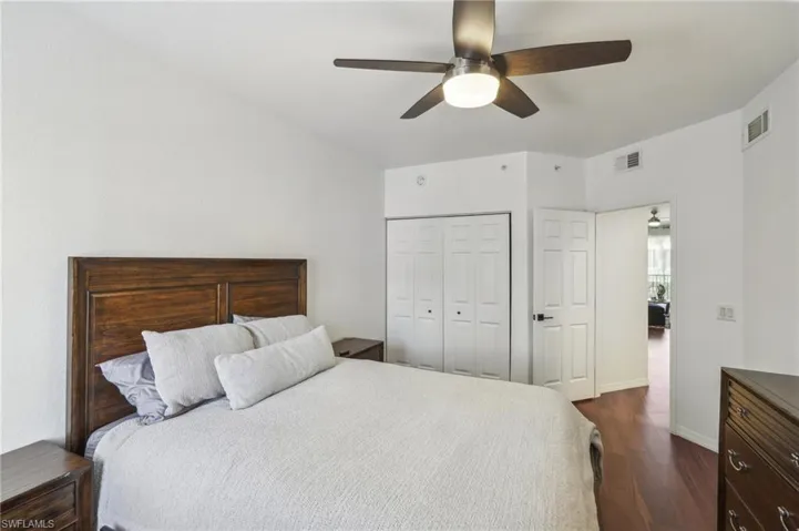 Bedroom featuring a closet, visible vents, baseboards, ceiling fan, and dark wood-style floors