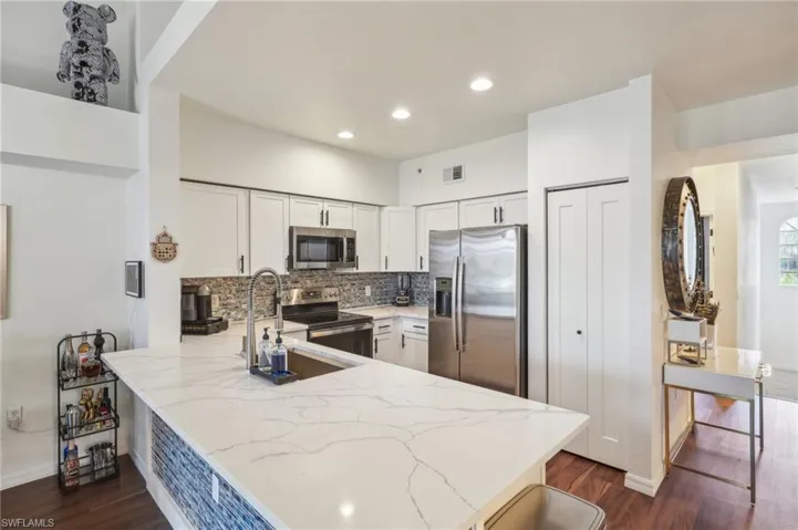 Kitchen featuring white cabinetry, stainless steel appliances, backsplash, visible vents, and a peninsula