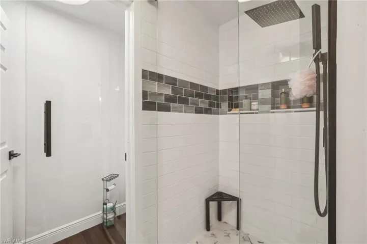 Bathroom with baseboards, a tile shower, and wood finished floors