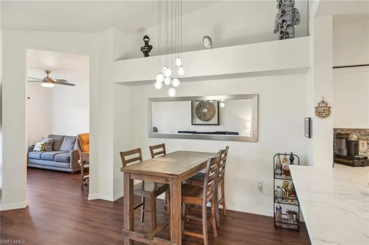 Dining space with baseboards, ceiling fan, wood finished floors, and a wood stove