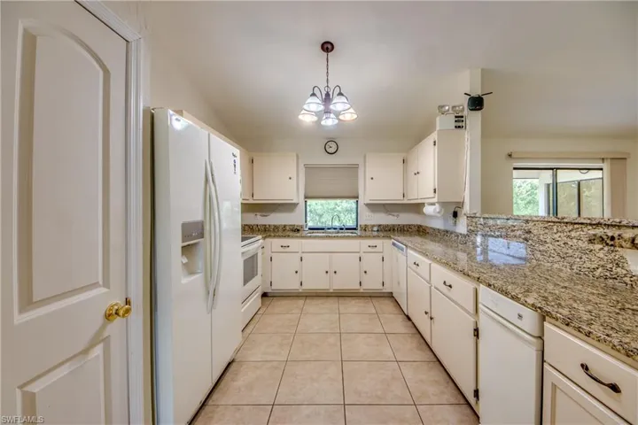 Kitchen with white appliances, Granite Counters. Plenty of cabinets & pantry on left.