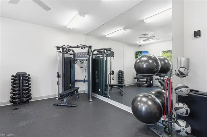 Fitness center with rubber flooring, full-height wall mirrors, and ceiling fan