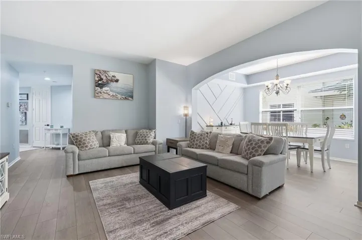 Wood-finish flooring throughout, arched entryway, tray ceiling, and decorative wall paneling