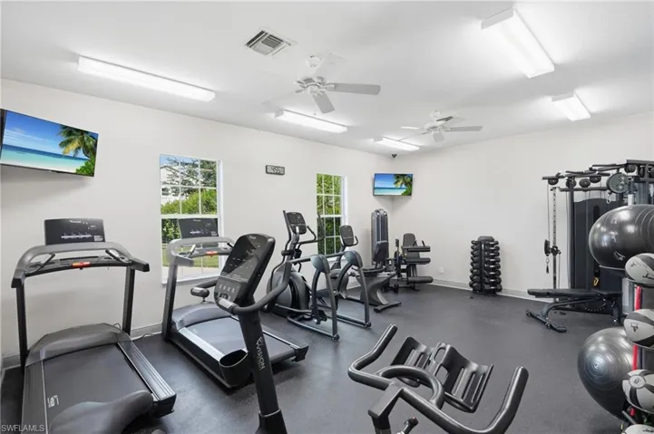 Spacious fitness area featuring multiple windows, recessed lighting, ceiling fans, and durable rubber flooring