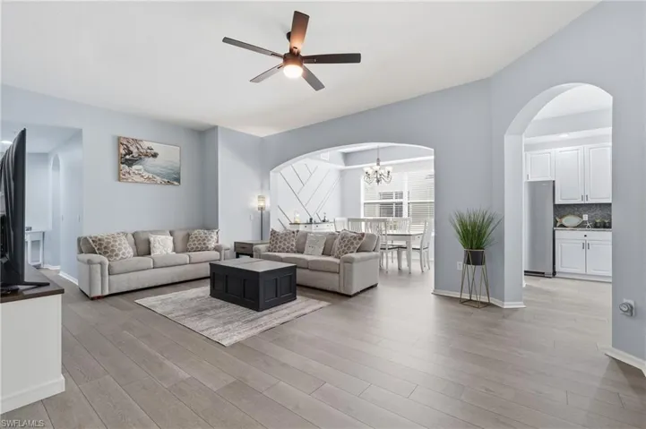 Open-concept living area featuring engineered wood-finish flooring throughout, recessed ceiling lighting, and a ceiling fan with integrated light fixture
