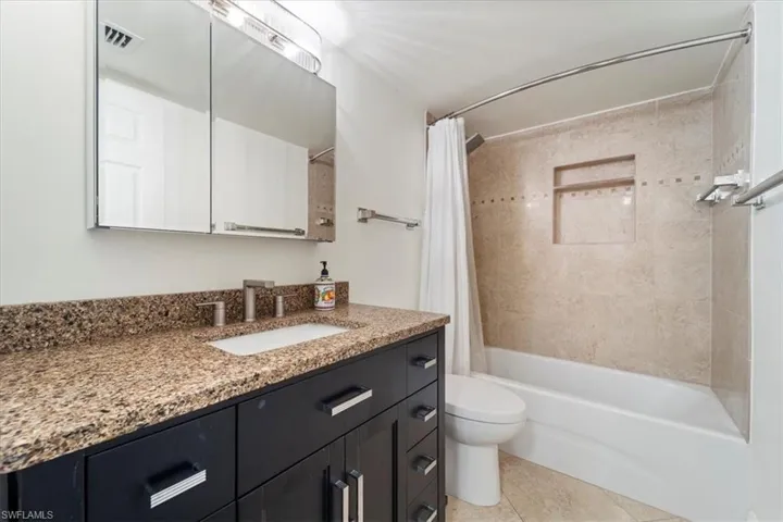 Full bath with vanity, shower / tub combo, and light tile patterned flooring