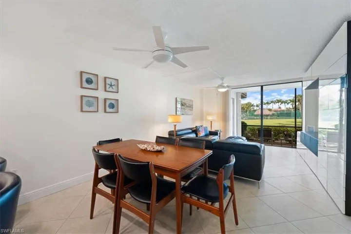 Dining space with a wall of windows, light tile patterned flooring, and a ceiling fan