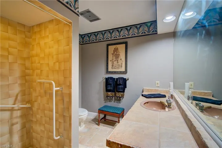 Full bathroom featuring vanity, tiled shower, stone tile flooring, and recessed lighting