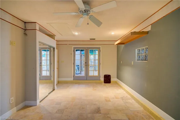 Spare room with french doors, ceiling fan, and stone finish flooring