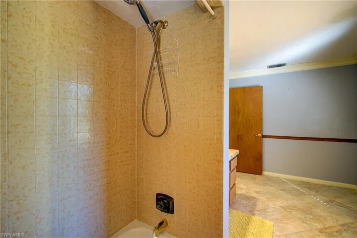 Bathroom featuring shower / bathtub combination, crown molding, vanity, and light stone finish flooring