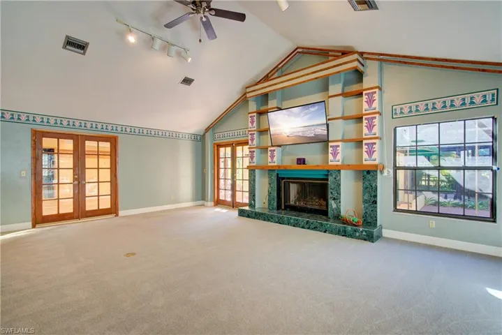 Unfurnished living room with french doors, light carpet, plenty of natural light, and high vaulted ceiling