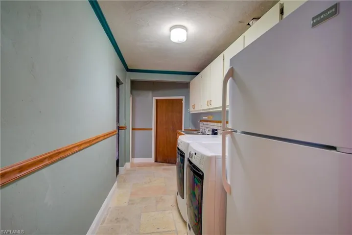 Washroom with stone tile floors, separate washer and dryer, cabinet space, and crown molding